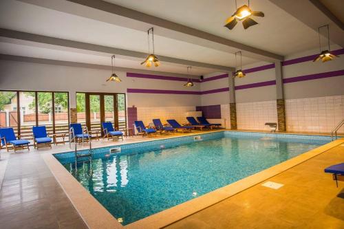 a swimming pool with blue chairs and chairs in a building at Pensiunea Edelweiss, Putna in Putna