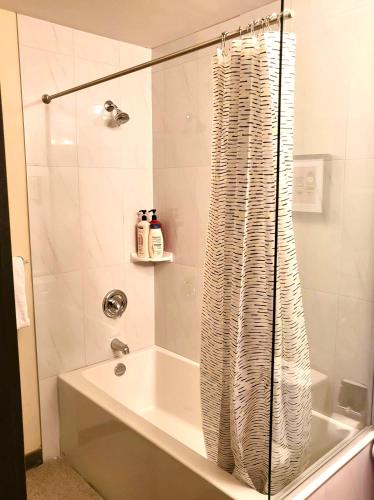 a bathroom with a shower curtain and a bath tub at B&B 2br 1pullout Grand Rockies Resort in Canmore