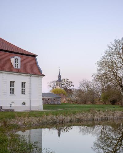 a white house with a church in the background at Jagdschloss Kotelow in Kotelow