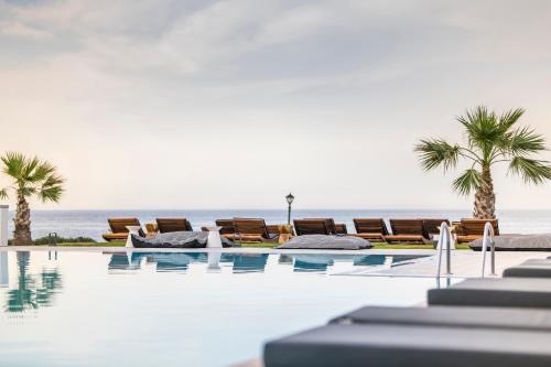 - une piscine avec des chaises et l'océan en arrière-plan dans l'établissement Insula Alba Resort & Spa (Adults Only), à Chersónissos