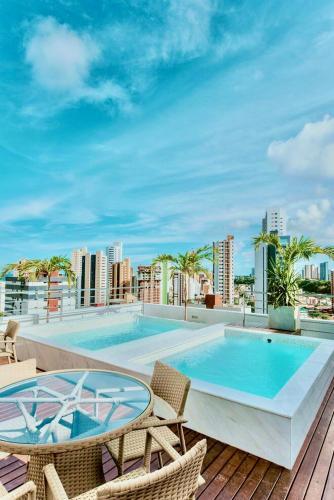 a swimming pool with chairs and a table on a balcony at PHGFlats Manaira apart hotel in João Pessoa