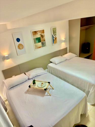 two beds in a hotel room with a tray of food at PHGFlats Manaira apart hotel in João Pessoa