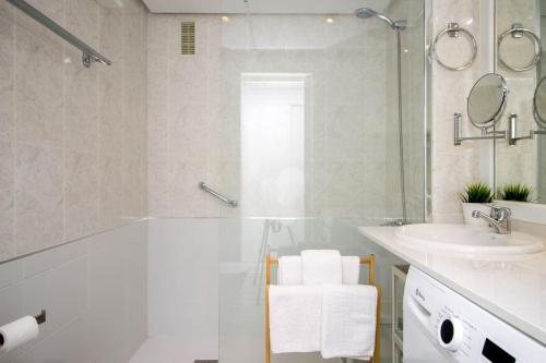 Baño blanco con lavabo y bañera en Ocean House Bloque 3 Planta 1 By IVI Real Estate, en Torremolinos