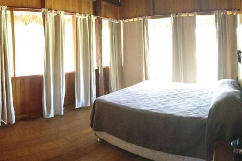 馬爾多納多港的住宿－Rustic Cabin - Tambopata Natural Reserve，一间设有白色窗帘的卧室和一张位于客房内的床