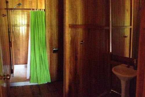 baño con cortina de ducha verde y lavamanos en Rustic Cabin - Tambopata Natural Reserve, en Puerto Maldonado