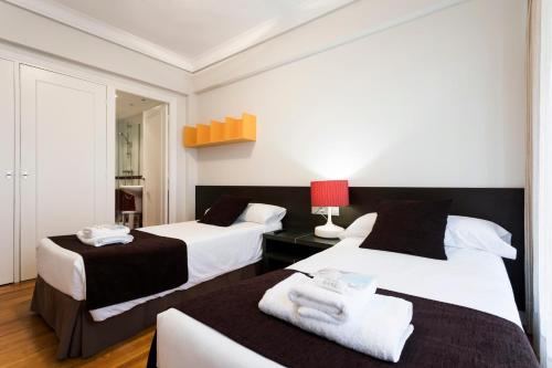 une chambre d'hôtel avec deux lits et une lampe rouge dans l'établissement Hondarribia by Basquelidays, à Fontarrabie