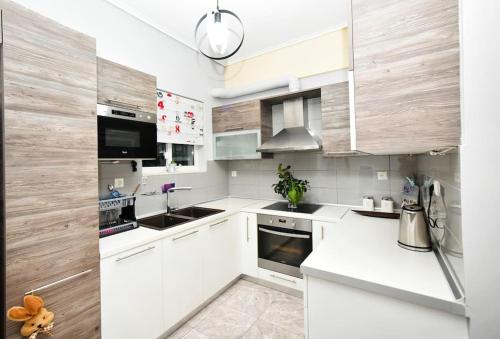 Biała kuchnia z drewnianymi ścianami i białymi szafkami w obiekcie Lili's Apartment w mieście Eleusis