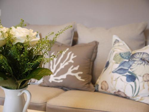 a couch with pillows and a vase with a plant at Hotel Ratsstuben in Lindau
