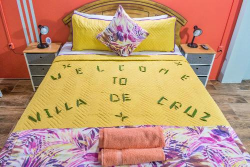 a bed with a yellow comforter with the words welcome to milano on at Villa De Cruz - Groovy Suite in Scarborough