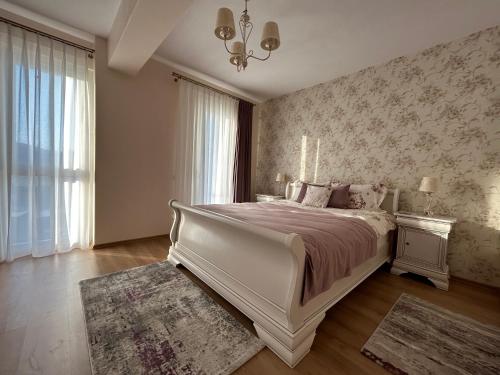 a bedroom with a large white bed and a window at Apartament Rose in Gura Humorului