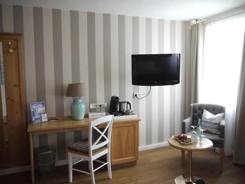 a hotel room with a desk and a tv on a wall at Hotel Ratsstuben in Lindau