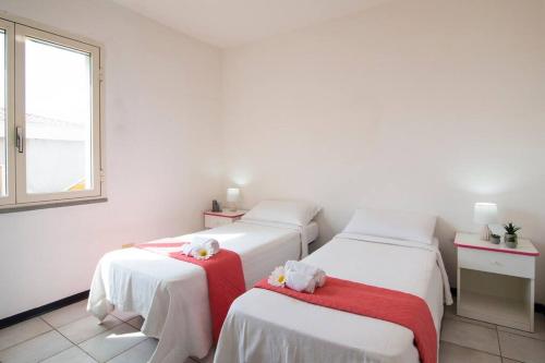 2 łóżka w pokoju z białymi ścianami i oknem w obiekcie [Torregrande]APT.2 - Vicino al mare - Free Wi-Fi w mieście Torre Grande