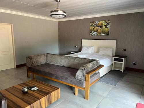 a bedroom with a bed and a couch and a table at Thabazimbi Country Lodge in Thabazimbi