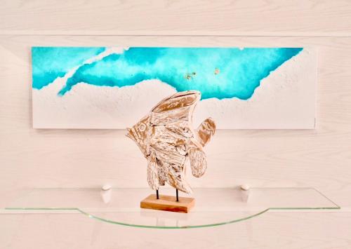 a bronze butterfly sculpture on a glass table in front of a painting at Hotel Neptuno in San Pedro del Pinatar