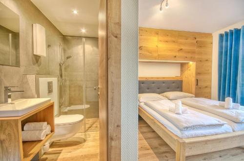 two pictures of a bathroom with a bed and a sink at Apartment Antonia - by Alpen Apartments in Zell am See