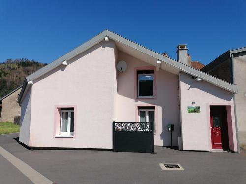 a white house with a red door at Gîte de rarounette au cœur des Vosges in Celles-sur-Plaine
