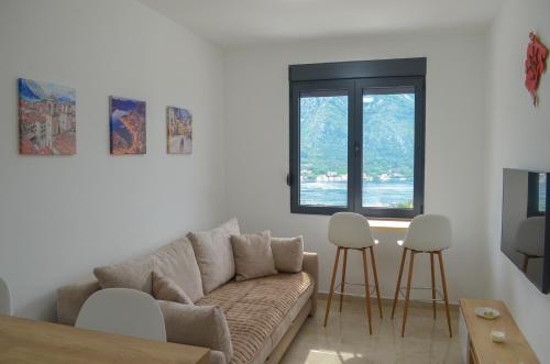 sala de estar con sofá y 2 taburetes en DM Apartments, en Kotor