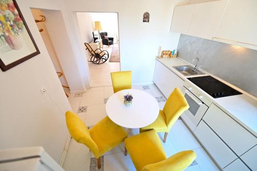 a kitchen with a white table and yellow chairs at Anna's Guest House in Sibiu