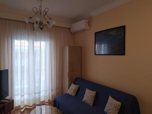- un salon avec un canapé bleu et une fenêtre dans l'établissement Cozy three BDRMS central APT at five Filippou str, à Thessalonique