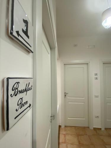 un corridoio con una porta bianca e un cartello sul muro di La Maison Derrière a Tropea
