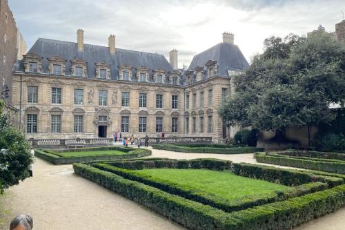a large building with a garden in front of it at Le Clos Des Vosges in Paris