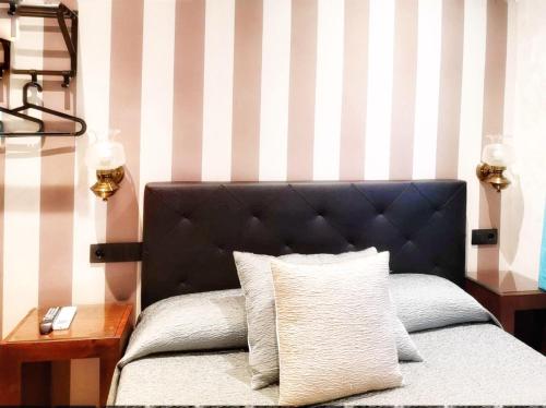 a bed with a black headboard and a side table at Hostal Plaza in Segovia