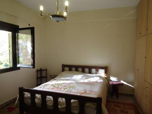 a bedroom with a bed and a window and a chandelier at Ανάμεσα στα Έλατα 