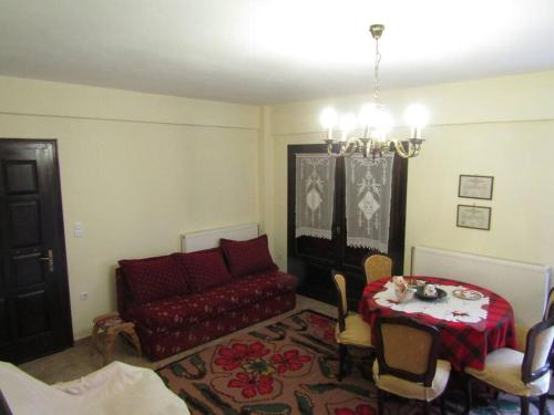 a living room with a red couch and a table at Ανάμεσα στα Έλατα in Ayía Varvára