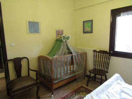 a room with a crib and two chairs and a window at Ανάμεσα στα Έλατα in Ayía Varvára