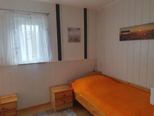 ein Schlafzimmer mit einem orangenen Bett und einem Fenster in der Unterkunft Ferienhaus Kabitschke in Dobbrikow