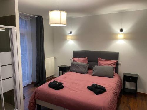 a bedroom with a large bed with two black towels on it at Bienvenue à la Villa Plagnal Classée 3 étoiles in Aubière