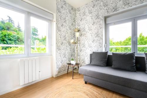 ein Wohnzimmer mit einem Sofa und 2 Fenstern in der Unterkunft Studio fonctionnel Lyon-Vaise-Saint Didier in Saint-Didier-au-Mont-dʼOr