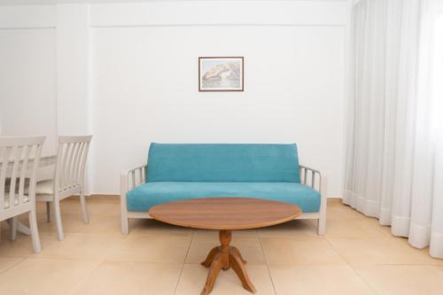 a living room with a blue couch and a table at Flora Hotel Apartments in Protaras