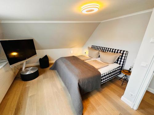 a bedroom with a bed and a flat screen tv at Meer-Lust-Sylt Haus Mateika in Westerland