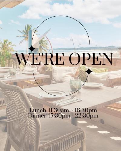 a table and chairs on a beach with the words were open at Luquillo Sunrise Beach Inn in Luquillo