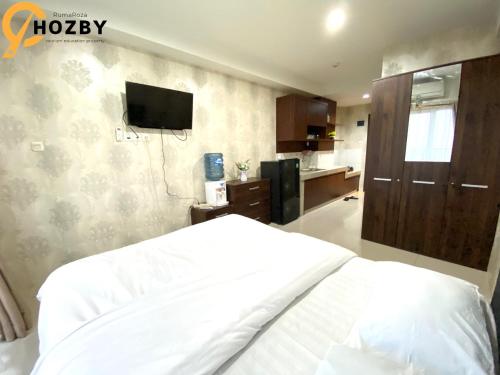 a bedroom with a bed and a tv on the wall at Hozby Skyview Setiabudi Suites in Sunggal