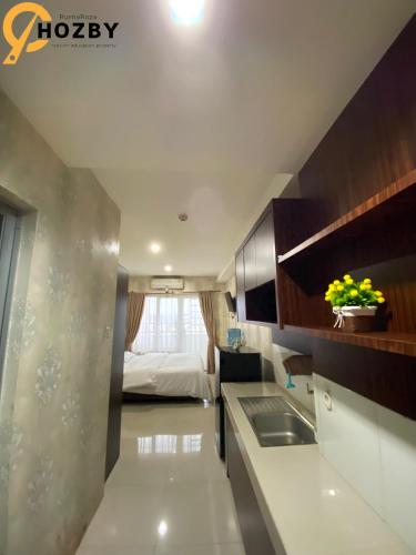 a kitchen with a sink and a bed in a room at Hozby Skyview Setiabudi Suites in Sunggal