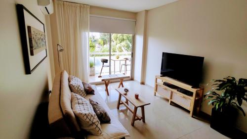 a living room with a couch and a flat screen tv at Avenida Aconquija Suites YB in Yerba Buena