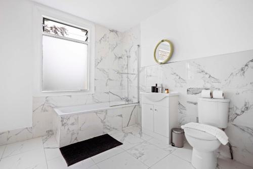 a white bathroom with a toilet and a sink at Parea Living - Hackney, 4-Bedroom Victorian House w Big Garden in London