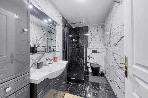 een zwart-witte badkamer met een wastafel en een douche bij Amazing apartment in a park overlooking Paris in Meudon