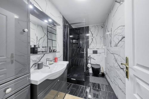 La salle de bains en noir et blanc est pourvue d'un lavabo et d'une douche. dans l'établissement Amazing apartment in a park overlooking Paris, à Meudon