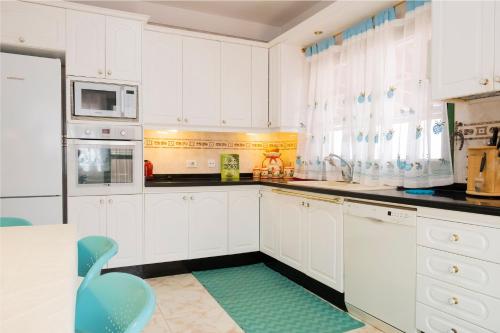 a kitchen with white cabinets and a blue chair at LIVE GUANCHES DE CANDELARIA in Candelaria
