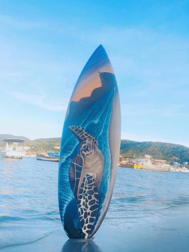 a surfboard with a mermaid on it sitting in the water at Encantos do mar in Arraial do Cabo