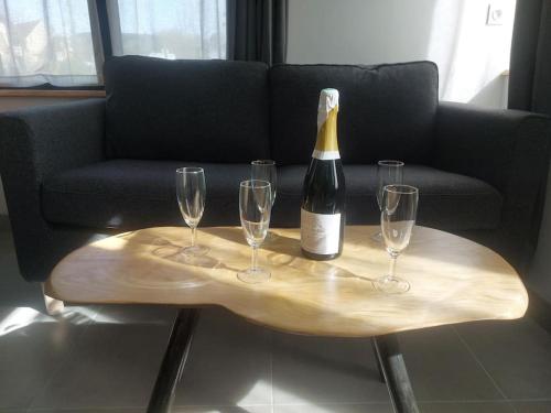 a bottle of wine on a wooden table with wine glasses at Le Héron in Thury-Harcourt