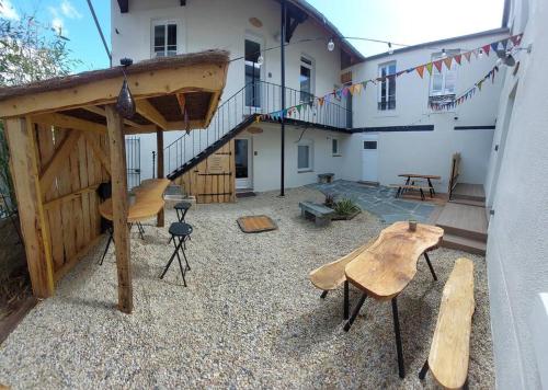 a patio with wooden tables and chairs in front of a building at Le Héron in Thury-Harcourt