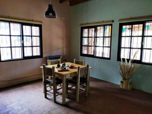 CASA EN MANANTIALES (Potrerillos, Mendoza) في بوتريريلوس: غرفة طعام مع طاولة وكراسي ونوافذ