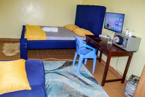 a bedroom with a bed and a desk with a computer at Trendy Homes Studio BnB in Bungoma