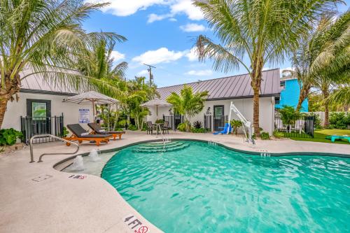 a swimming pool with palm trees in front of a house at The Retreat at Anna Maria Island Inn in Bradenton Beach