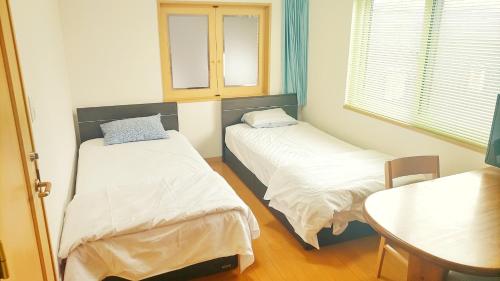 a small room with two beds and a table at Guest House Kingyo - Vacation STAY 14497 in Sapporo