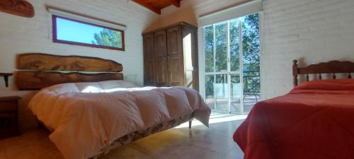 1 dormitorio con 2 camas y ventana en Cabañas La Gringa en Potrero de los Funes